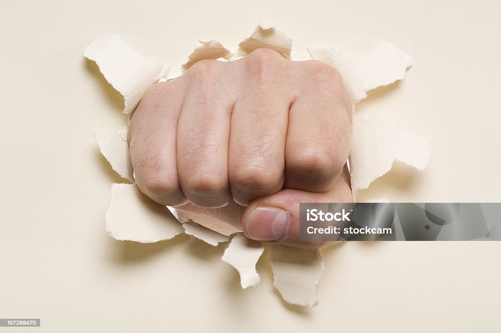 Fist punching through a ripped hole in a paper  Beige Stock Photo