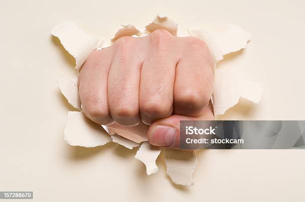 Fist Punching Through A Ripped Hole In A Paper Stock Photo - Download Image Now - Beige, Breaking, Broken