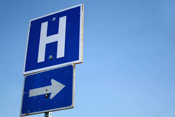 Blue Hospital sign, big H with Arrow against a clear blue sky, lots of copy space for your designs.