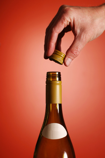 Taking the cap off a screw top bottle of white wine