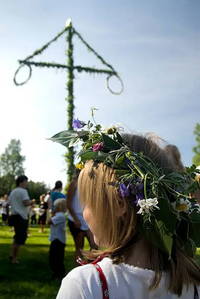 Little girl in front of the traditional maypole, watching people dancing, Sweden.