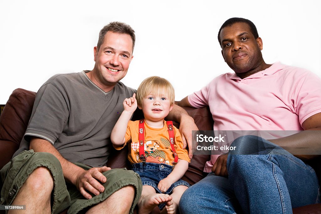 Niekonwencjonalny Wielorasowe rodziny dwóch mężczyzn, chłopiec siedzi na kanapie, uśmiecha się. - Zbiór zdjęć royalty-free (Dziecko)