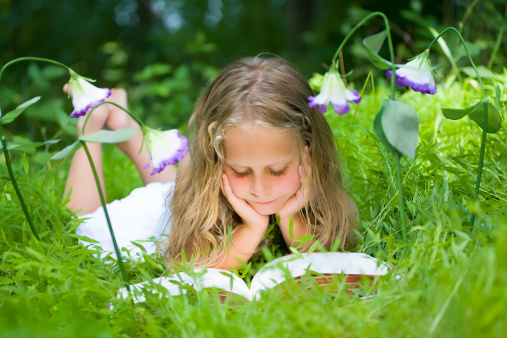Banner Asian Girl holding book reading at green park in nature garden. Panorama Young todler girl relaxation read book. Happy child women smiling with happiness. Kid sit in green park with copy space