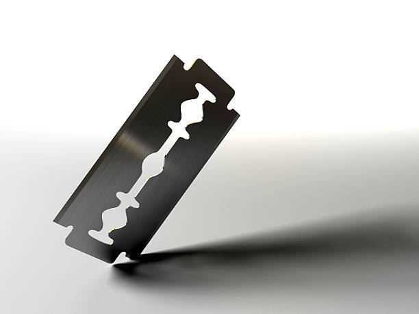 Razor blade on white background A razor blade cutting into a surface. 3D render with HDRI lighting and raytraced textures. razor blade stock pictures, royalty-free photos & images