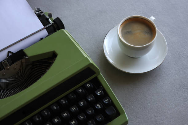 istock Old typewriter next to a cup of coffee against 1572907313