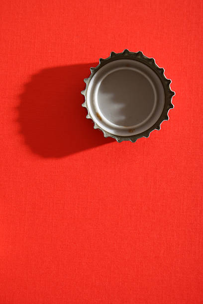Bottle cap Straight down shot of bottle cap. Hard light and long shadow over red textured paper beer bottle photos stock pictures, royalty-free photos & images