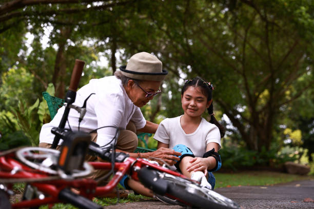 avó ajuda menina sentada de bicicleta após cair e sentir dor - acidente evento relacionado com o transporte - fotografias e filmes do acervo