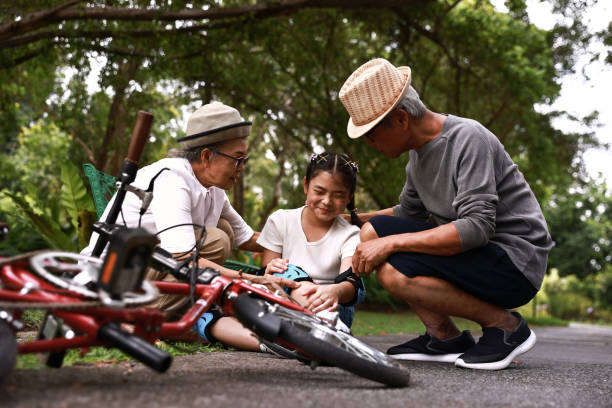 avô ajuda menina sentada de bicicleta após cair e sentir dor - acidente evento relacionado com o transporte - fotografias e filmes do acervo