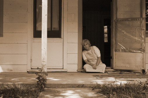 Woman sits in the doorway of her condemned house.