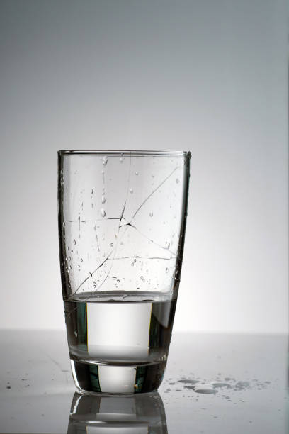 istock a broken glass filled with water and many splashed and droplet on the surface and table in back light 1572930501