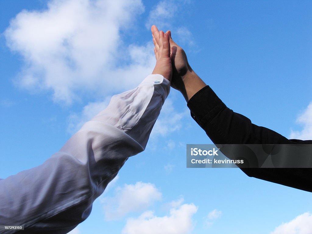 Dos personas proporcionando un alto cinco con cielo azul - Foto de stock de Número 5 libre de derechos