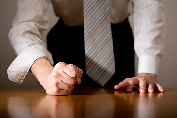 Close-up of a determined man with his fist on the table Businessman hitting table with clenched fist. bossy stock pictures, royalty-free photos & images