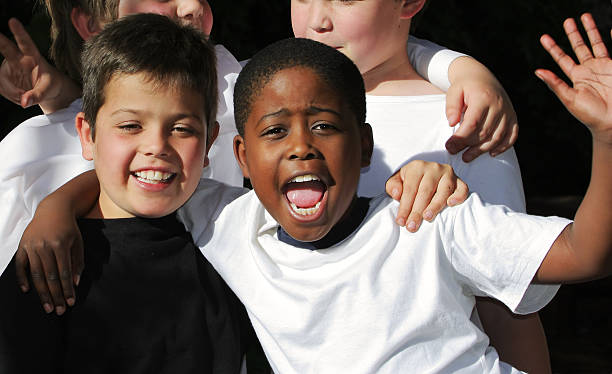 schoolboy multirracial amizade - embracing smiling gap children only - fotografias e filmes do acervo