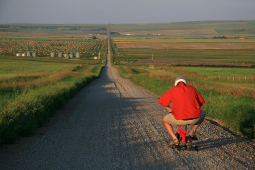 A man goes for a bike ride - but isn't going very far, very fast. Caucasian senior male going for a bicycle ride in a rural setting on a tiny children's bike. Humour. Additional themes include awkward, weird, strange, funny, cute, transportation, driving, cycling, country, dumb, idiot, and stupidity. 
