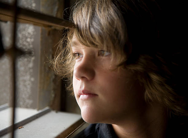istock Teenage Boy Looking Out Jail Window 157294629