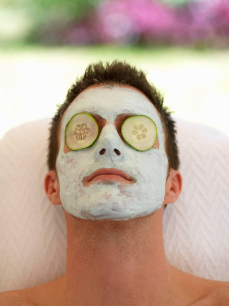 Facial A young man having facial treatment at a health spa. cucumber facial man stock pictures, royalty-free photos & images