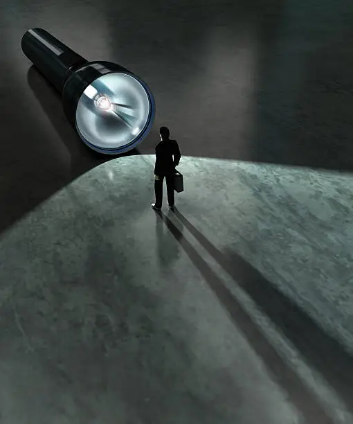 Photo of A business man standing in front of a large flashlight