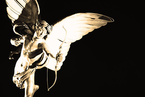 The famous Eros statue in the centre of Piccadilly Circus is illuminated to create a stark contrast against the night sky.