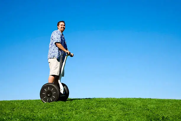 Photo of a young man enjoying a ride on his segway on a sunny summer day.