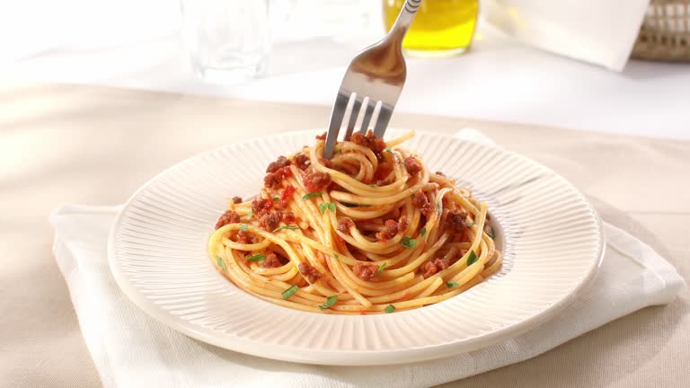 spaghetti bolognese is picked up with a fork. classic italian pasta with sauce.