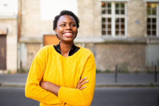 istock Joyful young african woman standing outdoors and looking away 1572983719