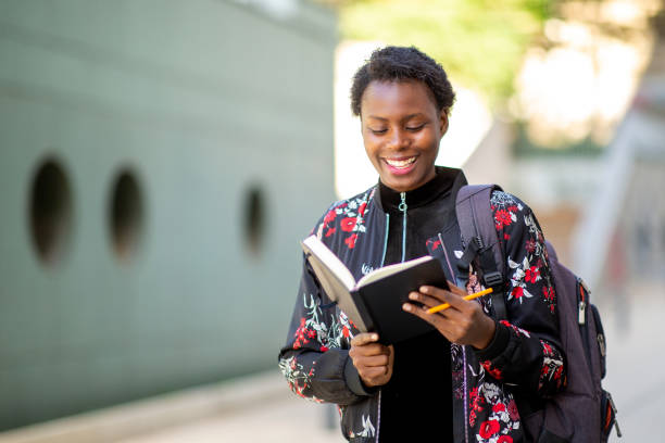 istock Happy african woman walking outside with book 1572984327