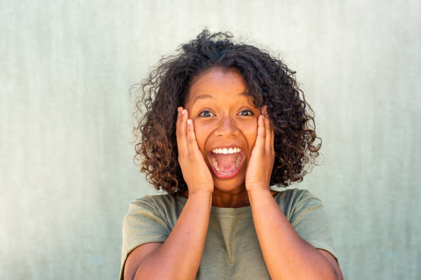 istock Close up surprised young woman with hands on face and mouth open surprised expression 1572985472