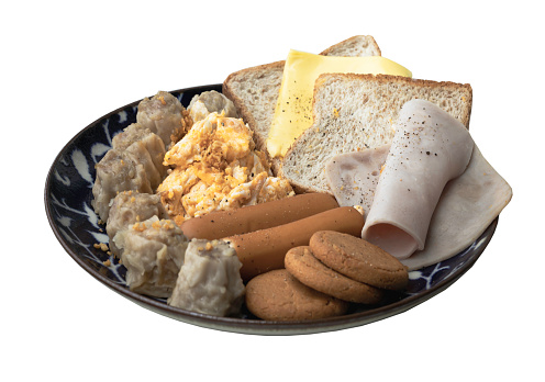 Homemade breakfast is including Breads, Fried sausages, Ham, Pork shumais, Scrambled eggs, Cheese, Crispy ginger cookies on ceramic plate isolated on white background with clipping path. Healthy food concept, Selective focus.