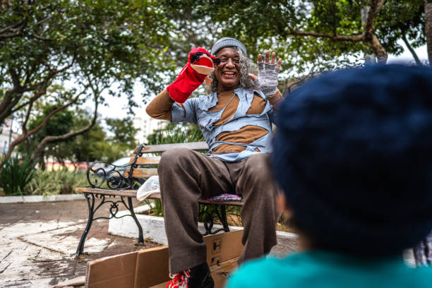 Senior homeless playing with a puppet outdoors
