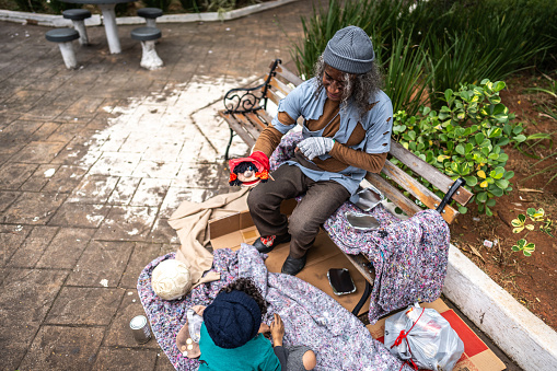 Senior homeless playing with a puppet outdoors