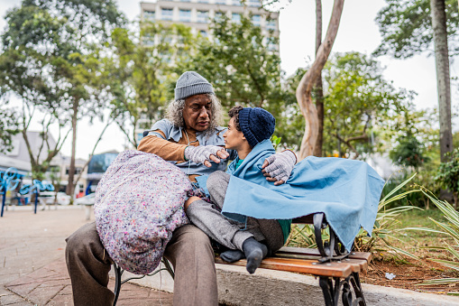 Senior homeless talking to his grandson outdoors