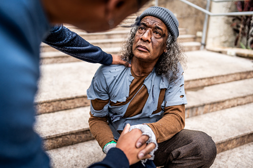 Man helping a senior homeless outdoors