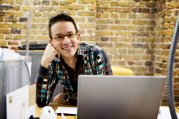 istock modern workplace: relaxed office professional sitting smiling at his desk 157305363