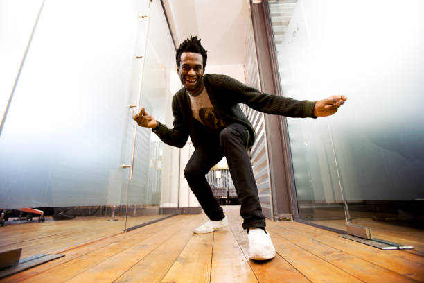 Make dancing toward a camera on the ground A relaxed and fun moment from a confident character creeping up on the low-angle camera in a contemporary creative office environment. click finger stock pictures, royalty-free photos & images