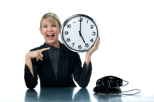 sonriente mujer agarrando reloj de oficina - wits end fotografías e imágenes de stock