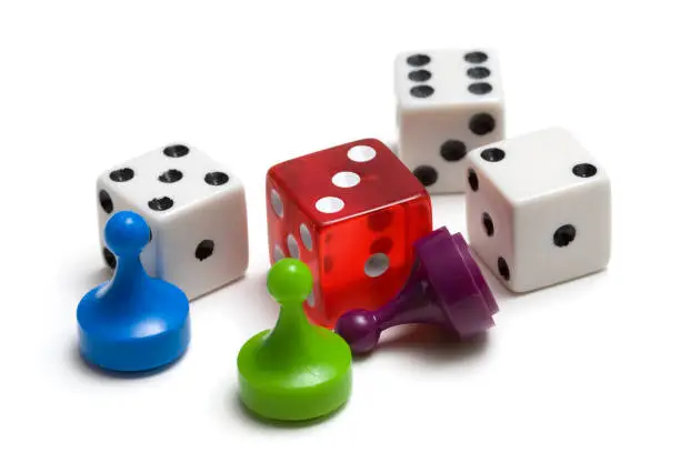 Photo of Three colored game pieces and four dice on white background