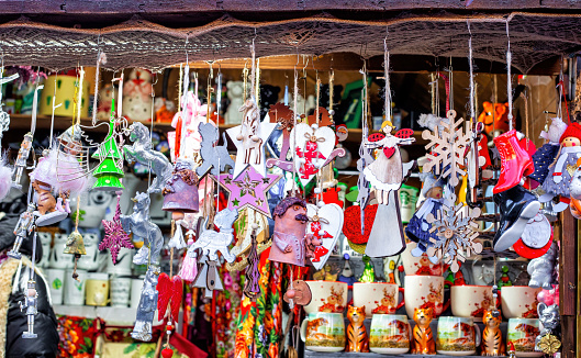 Christmas Fair selling wooden handmade toys on market square. Xmas market with traditional small colorful decorations. Holidays kiosk with festive multicolored gifts and souvenirs at city street