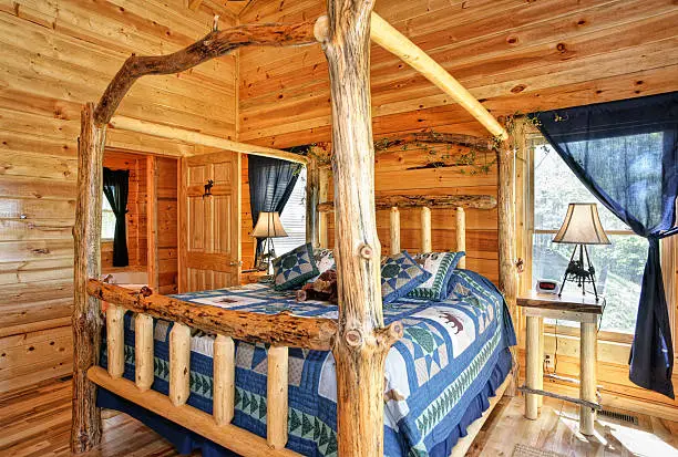 Modern log cabin bedroom with four-poster log bed.