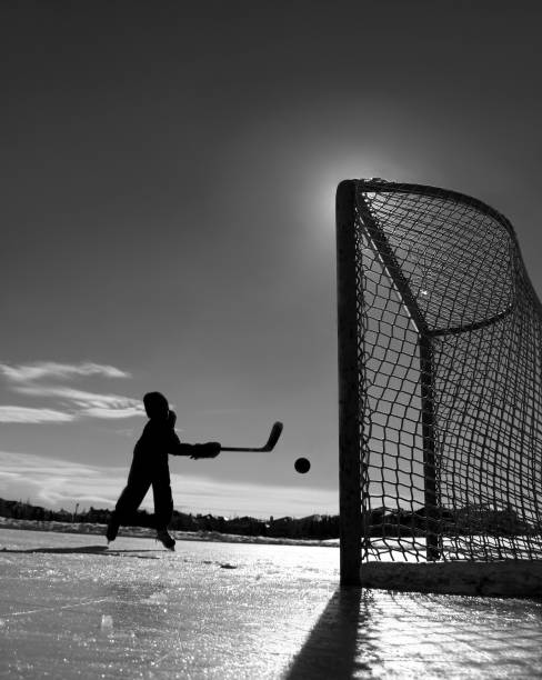 young boy playing al aire libre de hockey sobre hielo - slap shot fotografías e imágenes de stock