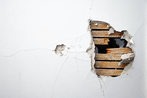 Cracked plaster, drywall and wood of a home's white wall stock photo