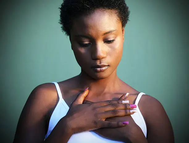 African woman with hands crossed against heart