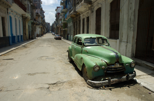 Rusting classic car slowly falling to pieces on a deserted Havana street