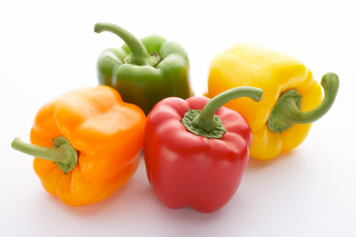 Four colorful bell peppers. Isolated on white background. Shallow DOF, selective focus.