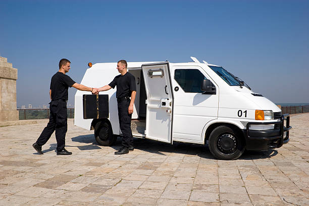 Two security members exchanging a case money transfer with two security guards and armoured van armored truck stock pictures, royalty-free photos & images