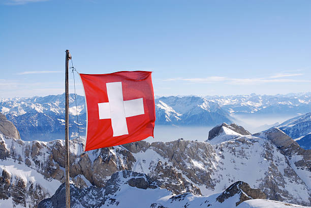 Swiss flag flying over snowy mountains stock photo