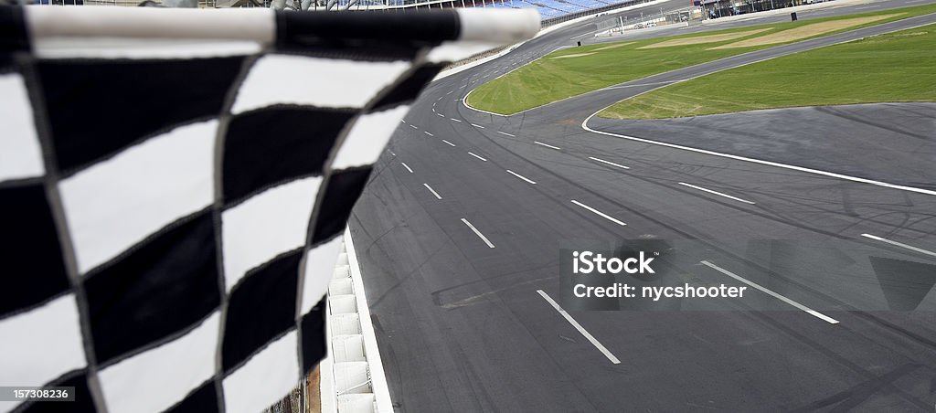 Checkered flag and motor speedway view from finish line with checkered flag waving at the race track. Stock Car Stock Photo