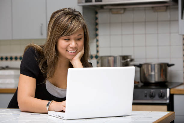 istock Asian Young Woman Using Laptop in Kitchen, Surfing the Web 157308256