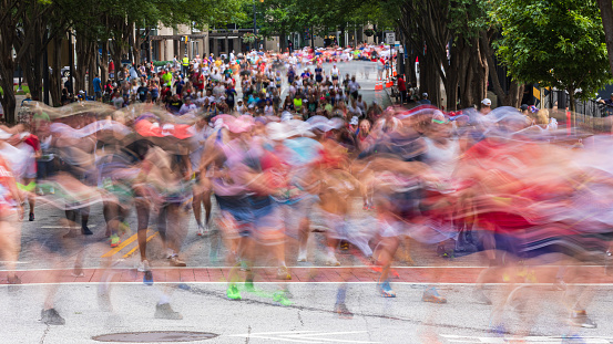 Motion blur shows thousands of unidentifiable runners running in the Atlanta Peachtree Road Race on July 4, 2023.