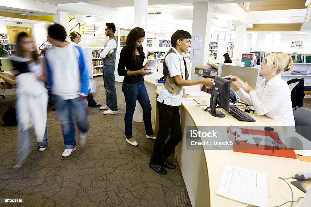 Jeunes étudiants: Image saisie sur le vif college bibliothèque de Bibliothécaire aider les élèves scène - Photo de Bibliothécaire libre de droits
