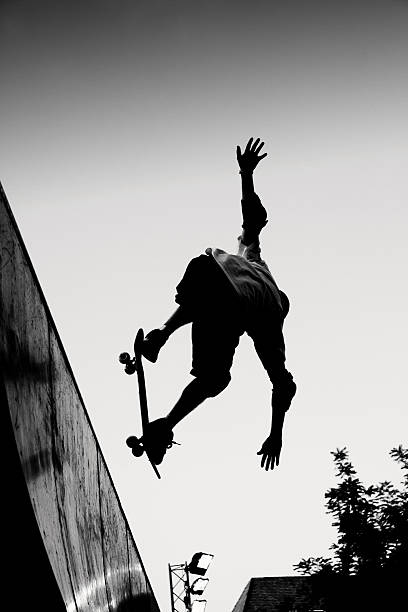 Black and white image of man performing a skateboard jump stock photo